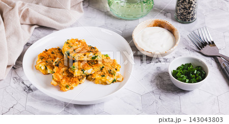 Appetizing fritters made from boiled eggs, green onions, and cheese, on a plate on the table web banner 143043803