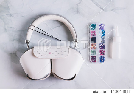 Close up of headphones in a case and a set of colorful rhinestones for decoration on the table top view 143043811