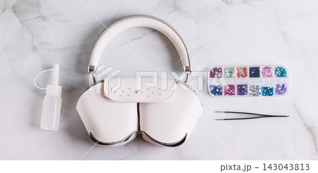The process of decorating a headphone case with colorful rhinestones on a table top view web banner The process of decorating a headphone case with colorful rhinestones on a table top view web banner 143043813