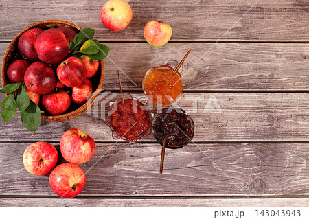 An assortment of preserves, fruit butters and fresh fruit purees arranged on wooden kitchen counter.Fresh apple butter or jam made from various apple varieties. home canning concept, banner 143043943