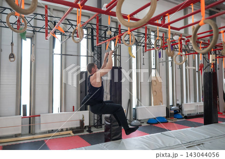 An athletic man practices at a ninja club's indoor obstacle course. 143044056