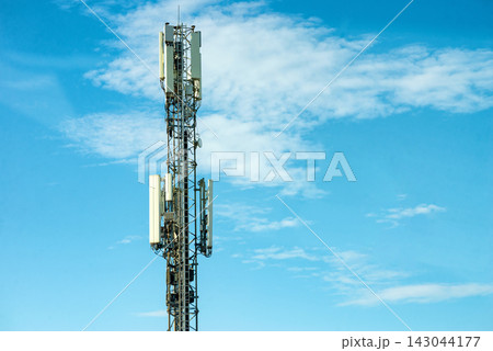 Mobile communication cell tower pole standing under bright blue sky clouds 143044177