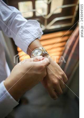 Man hand gesture Adjusting Luxury Wristwatch While Dressing In Shirt, executive man Morning Routine And Time Management Man hand gesture Adjusting Luxury Wristwatch While Dressing In Shirt, executive man Morning Routine And Time Management 143044505
