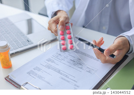 Medical doctor writing prescription form for patient treatment plan in modern office 143044552