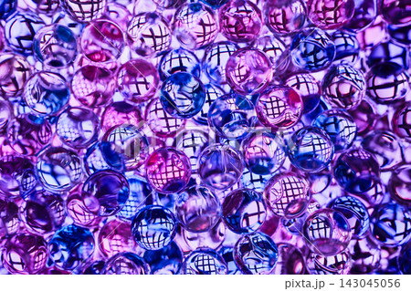 Transparent glass or gel balls with reflection of mesh grid inside each ball, illuminated in blue-violet-pink color scheme 143045056