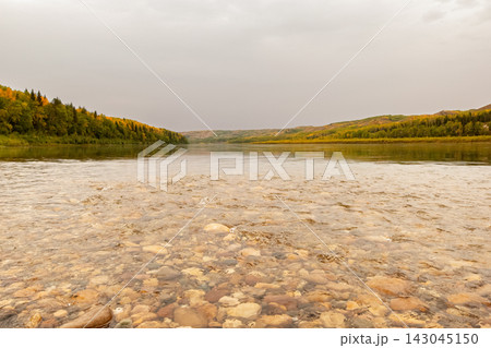 Calm warm autumn day at the river among yellow forests. 143045150