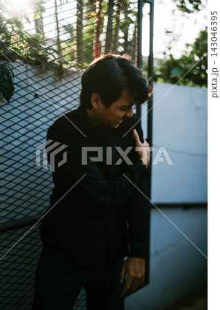 Man in black shirt standing by metal fence 143046395