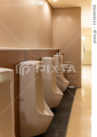 木目調の壁と白い小便器が並ぶモダンなトイレ空間 143046568