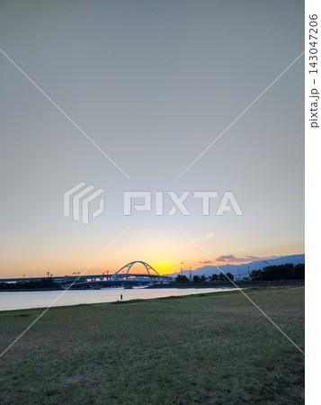 黄昏時の開放的な芝生広場とアーチ橋に沈む夕日（甲子園浜海浜公園） 143047206