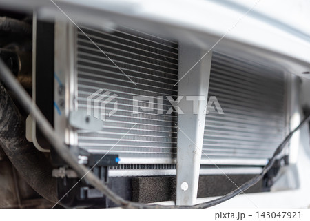 Close view of an automotive radiator cooling components behind the front body panel showing metal fins hoses supports vehicle heat management system Close view of an automotive radiator cooling components behind the front body panel showing metal fins hoses supports vehicle heat management system 143047921