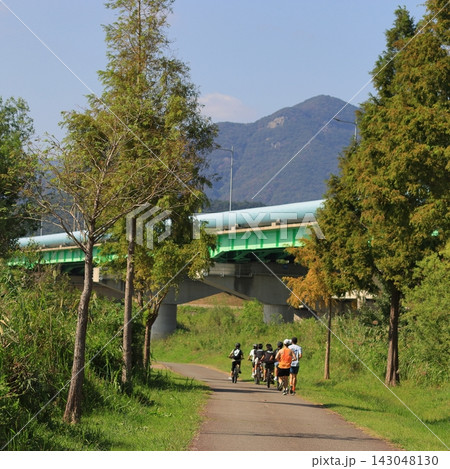 Cyclists and Runners on a Riverside Trail 143048130