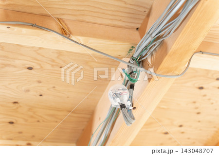 新築木造住宅の電気配線。天井裏の梁にまとめられた電線と配線工事 143048707