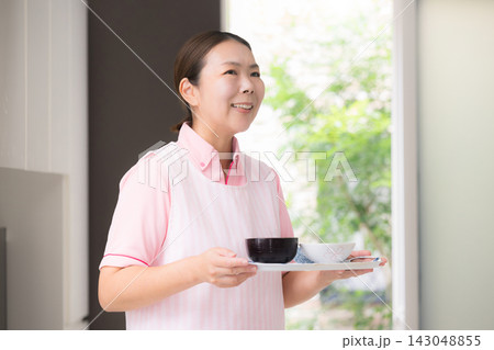 家事代行で食事を配膳する女性スタッフ、訪問介護、ホームヘルパー、生活援助、料理や食事準備をすイメージ 143048855