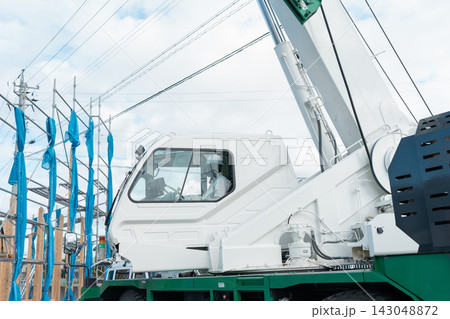 木造住宅の建築現場で作業するクレーン車。上棟を支えるクレーンオペレーター 木造住宅の建築現場で作業するクレーン車。上棟を支えるクレーンオペレーター 143048872