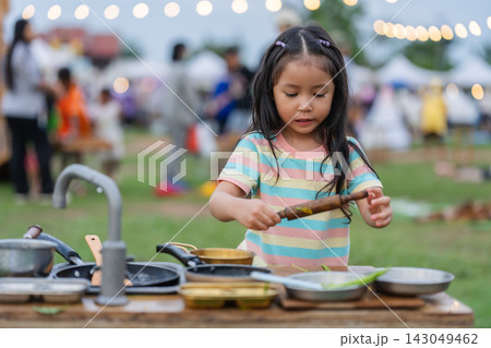 preschool child girl playing chef with toy kitchen set in park preschool child girl playing chef with toy kitchen set in park 143049462