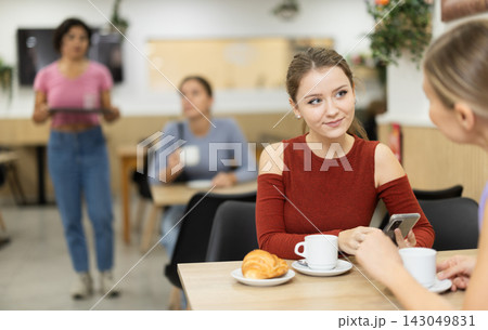In cafe, girl chatting sweetly during tea party with girl buddy In cafe, girl chatting sweetly during tea party with girl buddy 143049831