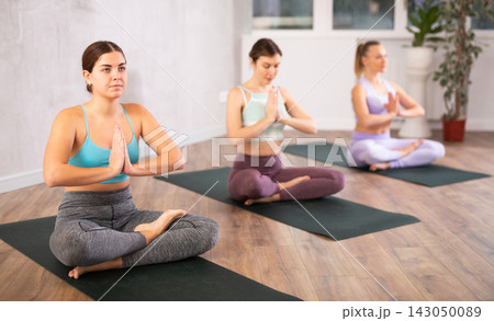 Young girl sitting in Padmasana yoga position with arms in namaste Young girl sitting in Padmasana yoga position with arms in namaste 143050089