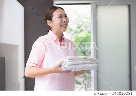 家事代行で洗濯をする女性スタッフ、訪問介護、ホームヘルパー、生活援助、洗濯物を運ぶ家事手伝いサービス 家事代行で洗濯をする女性スタッフ、訪問介護、ホームヘルパー、生活援助、洗濯物を運ぶ家事手伝いサービス 143050251