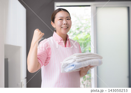 家事代行で洗濯をする女性スタッフ、訪問介護、ホームヘルパー、生活援助、洗濯物を持つガッツポーズ 143050253