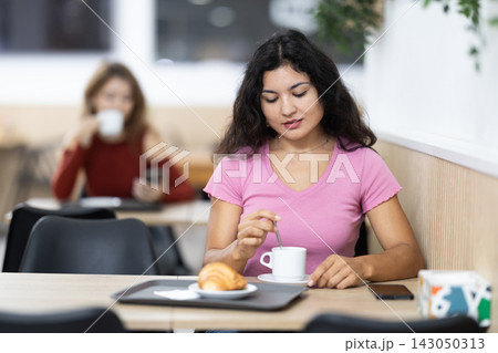 Attractive female sitting alone at table in cozy cafe, drinking fragrant coffee Attractive female sitting alone at table in cozy cafe, drinking fragrant coffee 143050313