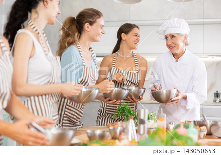 Elderly woman teaching cooking to group of woman 143050653