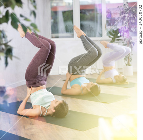 Young woman practicing shoulderstand in yoga studio Young woman practicing shoulderstand in yoga studio 143050702