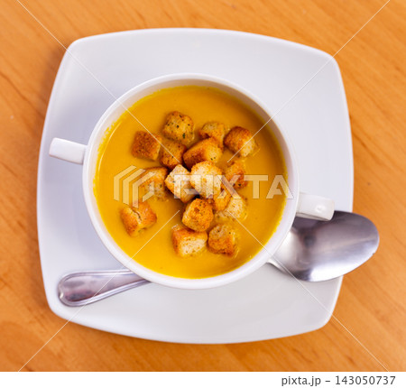 Plate is filled with homogeneous cream soup, dish made from seasonal vegetables and zucchini Plate is filled with homogeneous cream soup, dish made from seasonal vegetables and zucchini 143050737