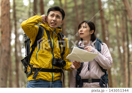 森で地図を見て道に迷う登山姿の男女 143051344