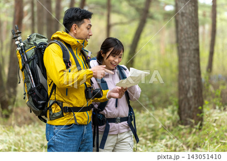 森の中で地図を確認しながら相談する男女の登山者 143051410