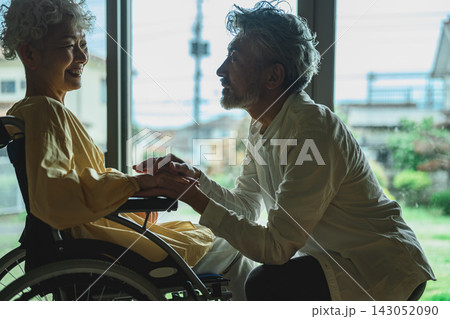 夫が車椅子の妻に寄り添い、手を握り励ます 夫が車椅子の妻に寄り添い、手を握り励ます 143052090