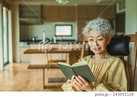 椅子に座って本を読む高齢女性 椅子に座って本を読む高齢女性 143052126