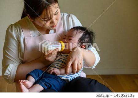 哺乳瓶でミルクを飲ませる母親と泣いている赤ちゃん 143052138