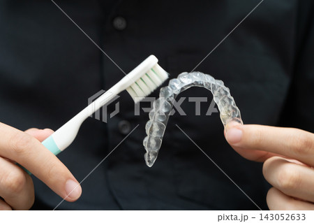 Man clean teeth brace removable retainer with brush. Man clean teeth brace removable retainer with brush. 143052633