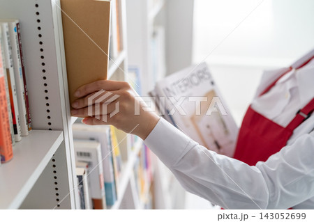 本棚に本を並べる書店員の女性の手元 143052699