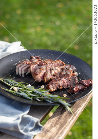 Freshly Grilled Beef Steak Slices on black plate at Outdoor Garden Picnic Freshly Grilled Beef Steak Slices on black plate at Outdoor Garden Picnic 143053073