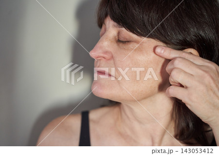 Middle-Aged Woman Pressing Temple With Fingertip While Eyes Closed In Indoor Profile Portrait 143053412
