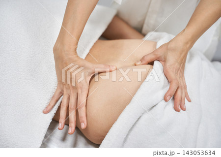 Therapist Massaging Lower Back With Firm Hand Pressure During Relaxation Session On White Towel 143053634