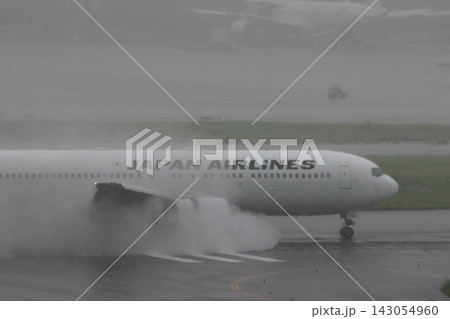 雨の滑走路に着陸する旅客機　エンジンの逆噴射の水煙　 143054960