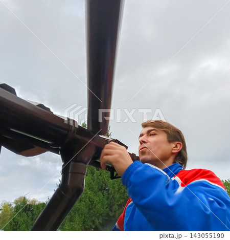 Handyman installing a roof gutter downspout on a residential house 143055190