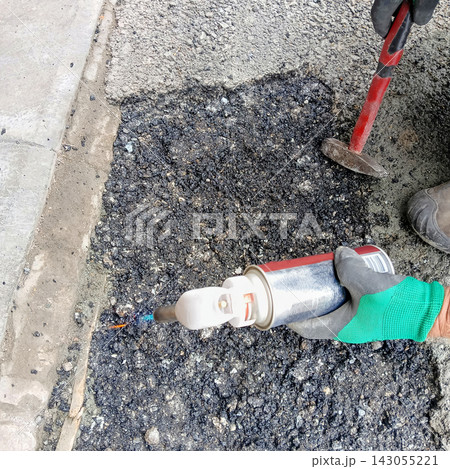 Worker using a gas torch for asphalt pavement repair Worker using a gas torch for asphalt pavement repair 143055221