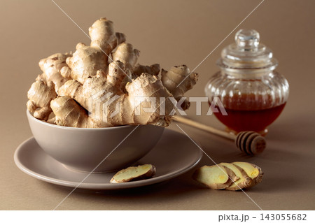 Ginger with honey jar on a beige background. 143055682