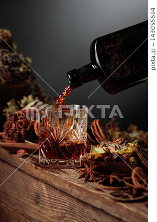 Herbal balm or tincture is poured from a vintage bottle into a glass. 143055694