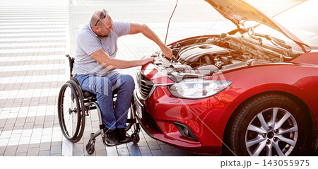Disabled man in wheelchair check engine his car at parking Disabled man in wheelchair check engine his car at parking 143055975