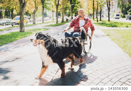 Happy young man with a physical disability in a wheelchair with his dog. Happy young man with a physical disability in a wheelchair with his dog. 143056300