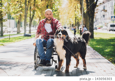 Happy young man with a physical disability in a wheelchair with his dog. Happy young man with a physical disability in a wheelchair with his dog. 143056303