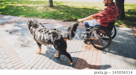 Happy young man with a physical disability in a wheelchair with his dog. 143056314