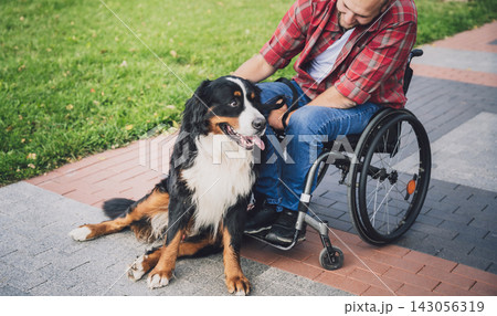 Happy young man with a physical disability in a wheelchair with his dog. Happy young man with a physical disability in a wheelchair with his dog. 143056319