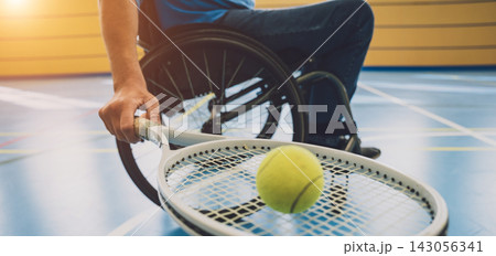 Adult man with a physical disability in a wheelchair playing tennis on indoor tennis court Adult man with a physical disability in a wheelchair playing tennis on indoor tennis court 143056341