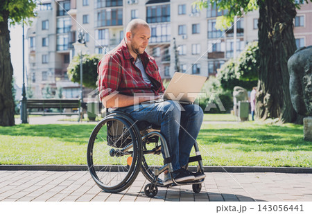 Freelancer with a physical disability in a wheelchair working at the park Freelancer with a physical disability in a wheelchair working at the park 143056441