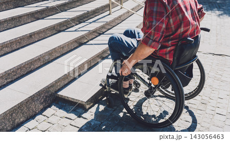 Young man with a physical disability in a wheelchair in front of the stairs Young man with a physical disability in a wheelchair in front of the stairs 143056463